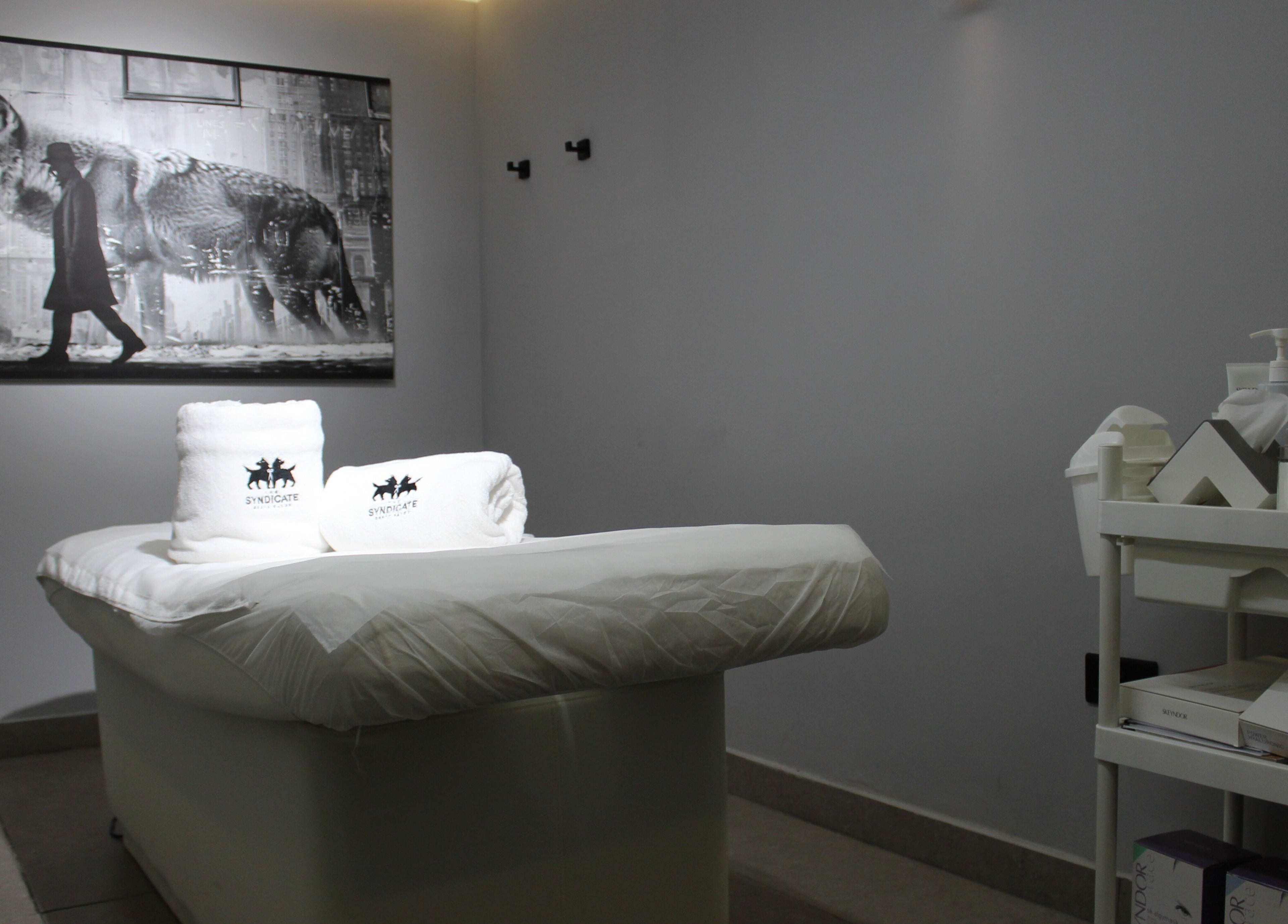 Relaxing treatment room at The Syndicate Gents Salon, Dubai, AE, featuring massage table and skincare products.
