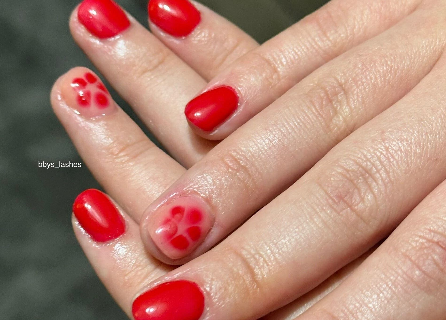 Vibrant red manicure with floral accent at Bbys Lashes & Nails, Sheffield, England, GB.