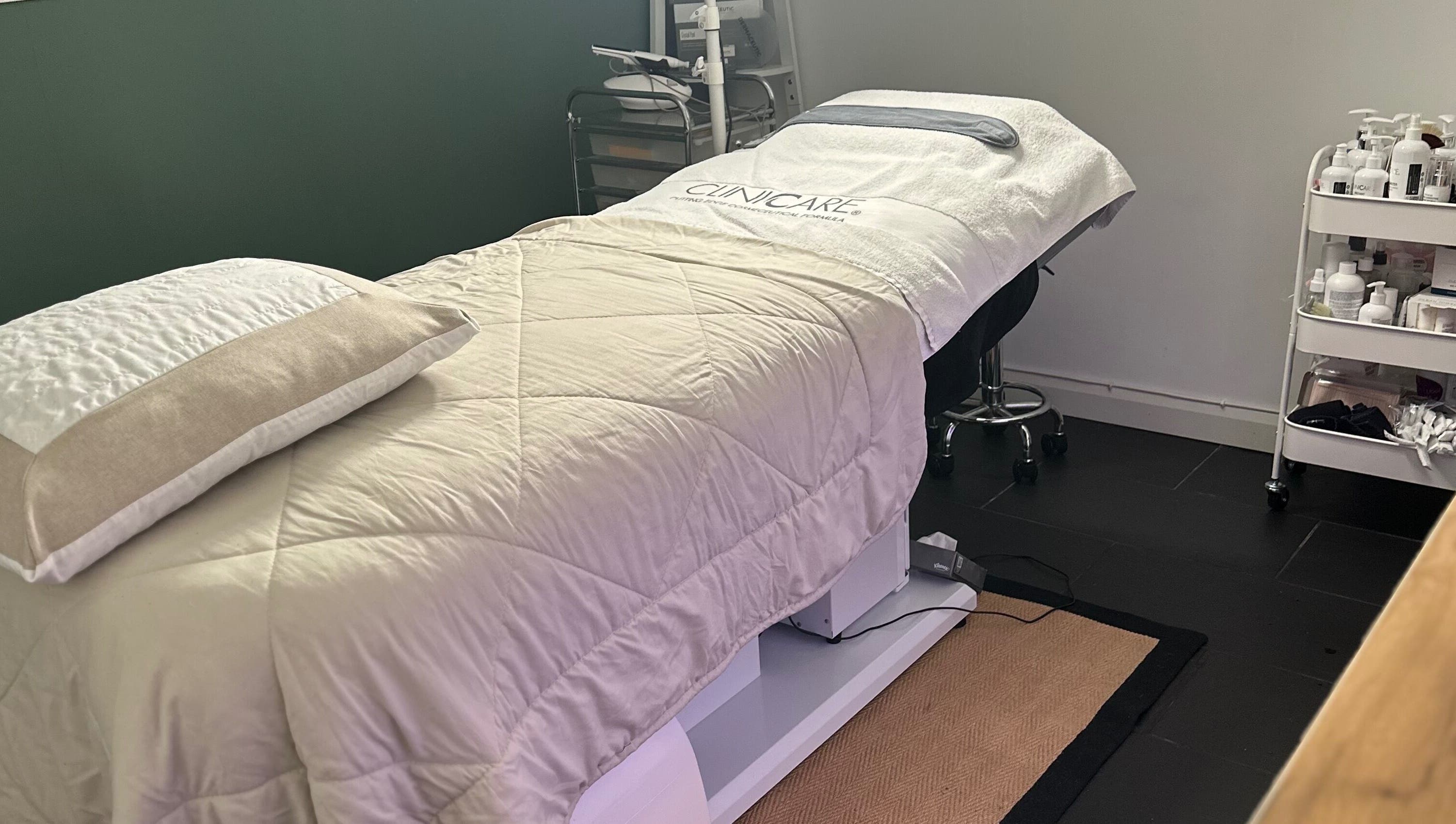 Cozy treatment room at The Renewed Lab, Harrold, England, GB, featuring a plush massage bed and skincare essentials.