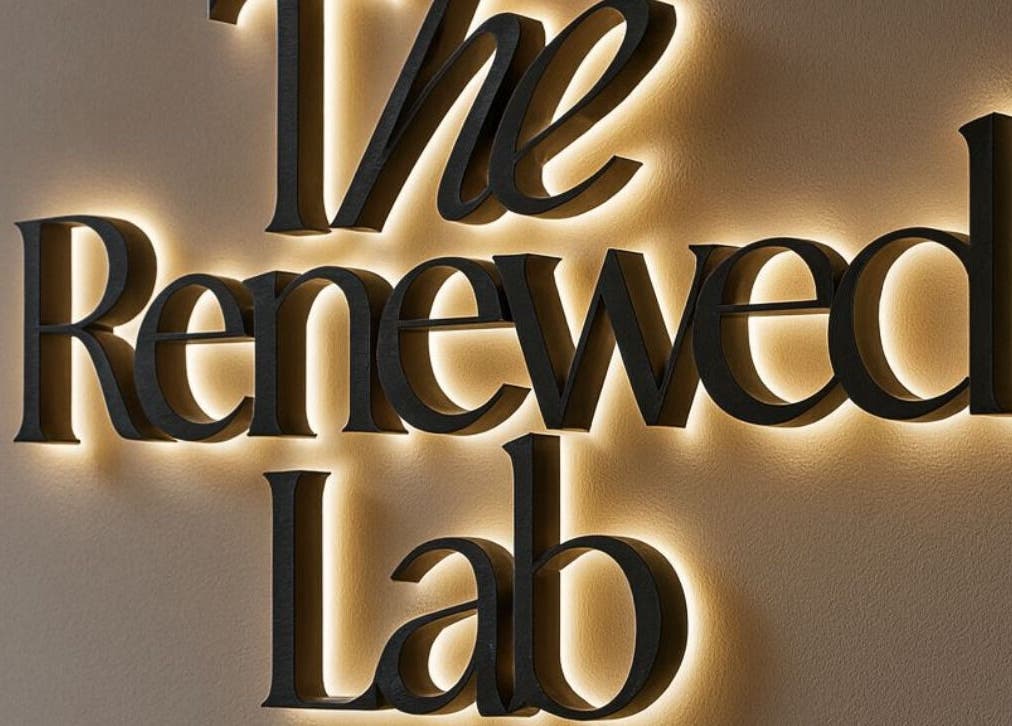 Illuminated sign of The Renewed Lab in Harrold, England, GB, showcasing elegant branding.