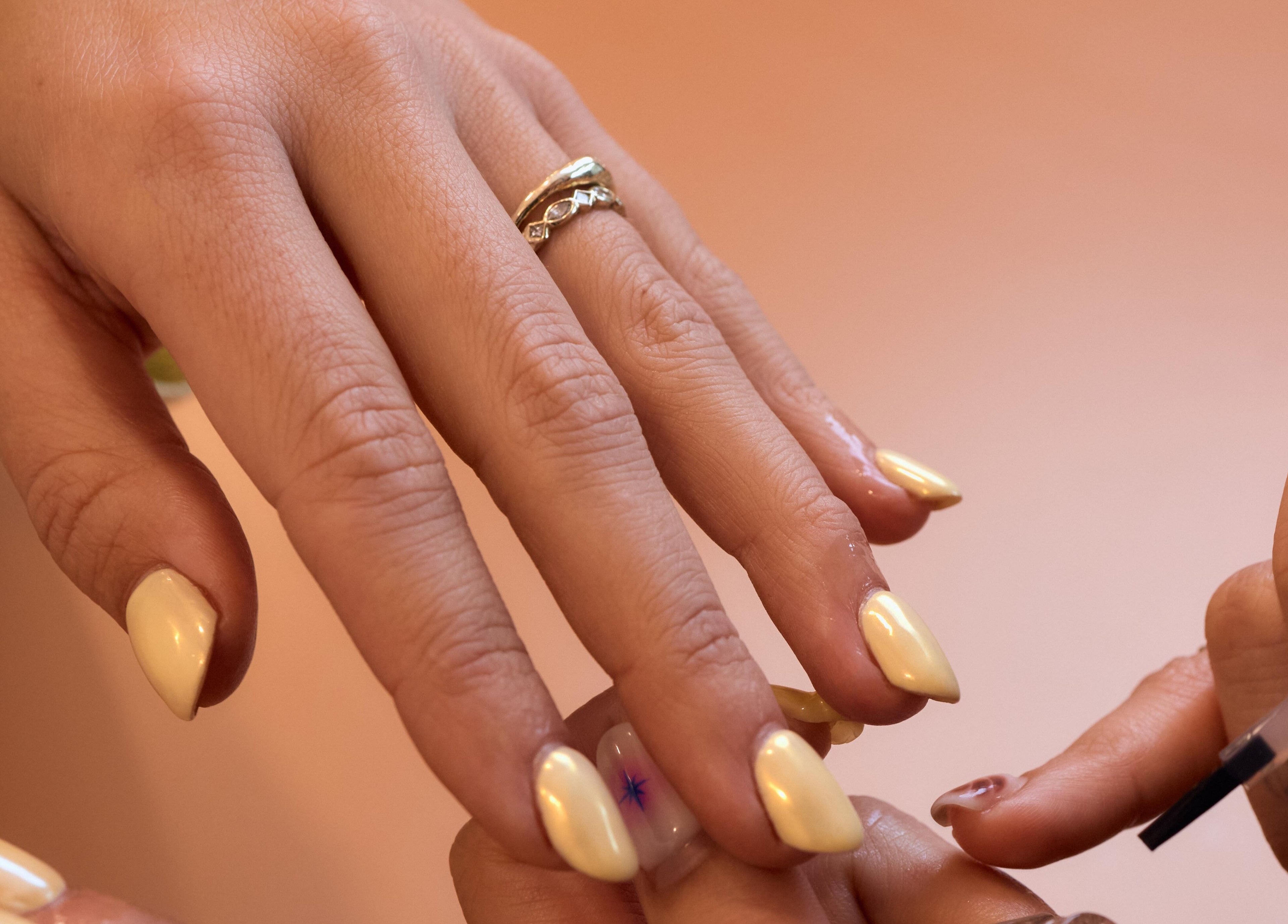 Close-up of a manicure at Painted, Darlinghurst, New South Wales, AU with glossy yellow nails.