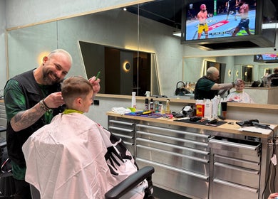 Admir the Barber giving a haircut to a child in Melbourne, Victoria, AU barber shop.