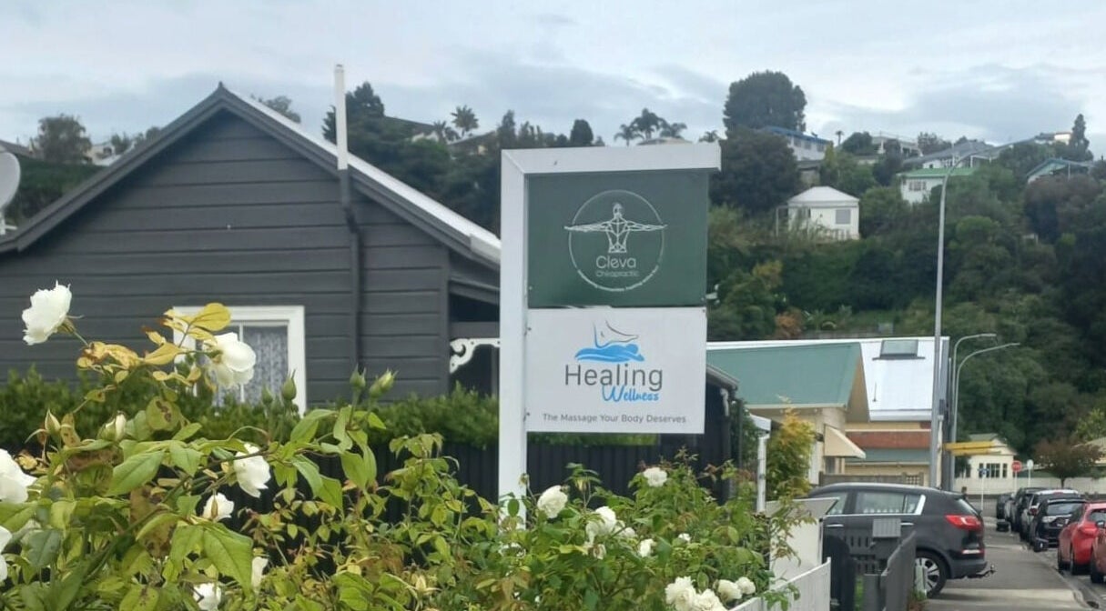 Healing Wellness NZ sign amidst lush garden in Napier, Hawke's Bay, NZ, inviting relaxation and rejuvenation.