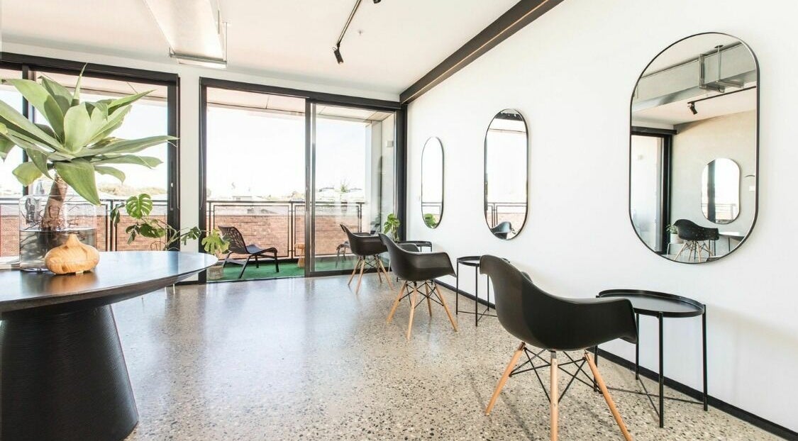 Stylish interior of Jorge Viota Hairdressing and Barbers in Melbourne, Victoria, AU, showcasing sleek chairs and mirrors.
