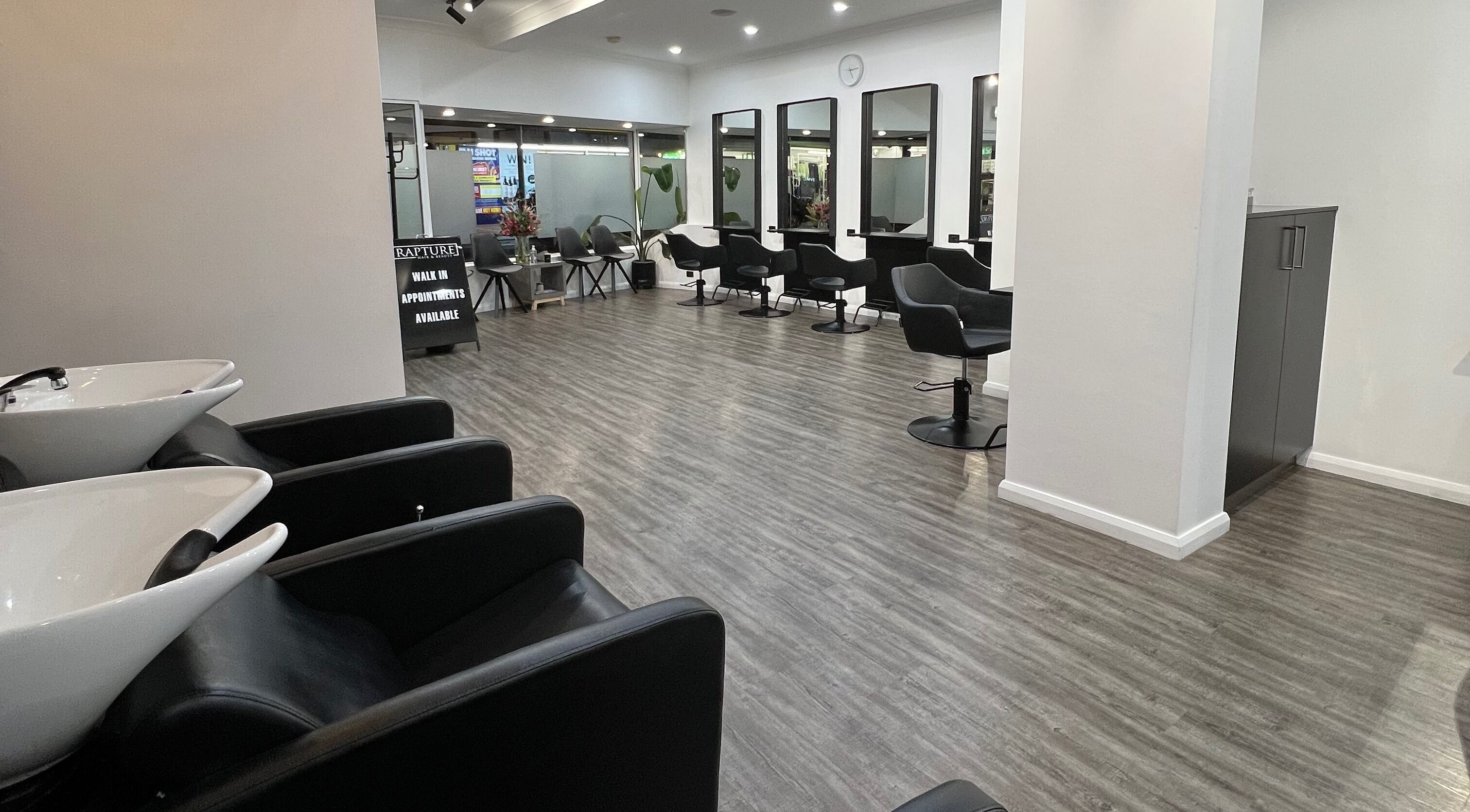 Modern interior of Rapture Hair and Beauty salon in Moonah, Tasmania, AU, featuring sleek styling chairs and mirrors.