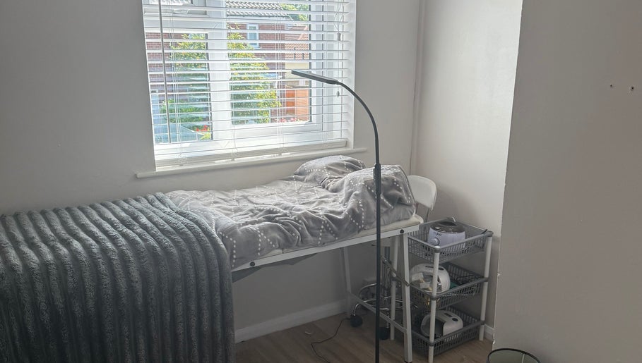 Beautybymill treatment bed with soft grey blankets under a window in Saltney Ferry, Wales, GB.