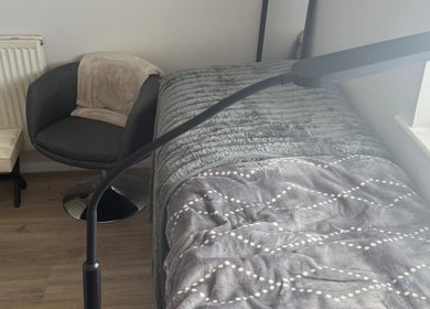 Comfortable treatment area at Beautybymill, Saltney Ferry, Wales, GB with cozy chair and plush bed.