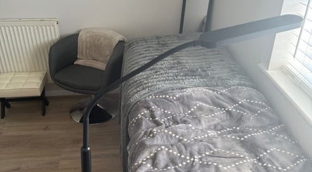 Comfortable treatment area at Beautybymill, Saltney Ferry, Wales, GB with cozy chair and plush bed.