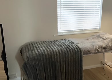 Cozy treatment bed in Beautybymill, Saltney Ferry, Wales, GB, by a bright window.