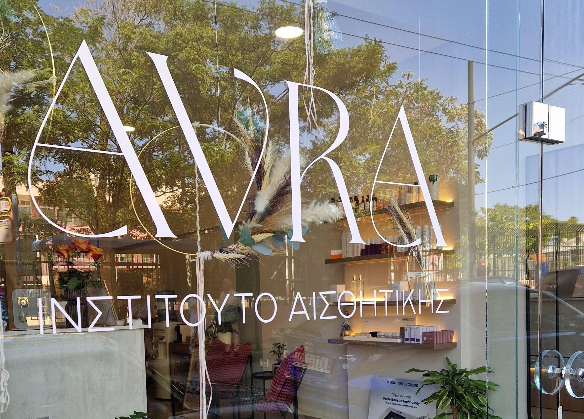 Η πρόσοψη του Avra Ινστιτούτο Αισθητικής στη Γαλάτσι, GR με αντανάκλαση δέντρων στο τζάμι.