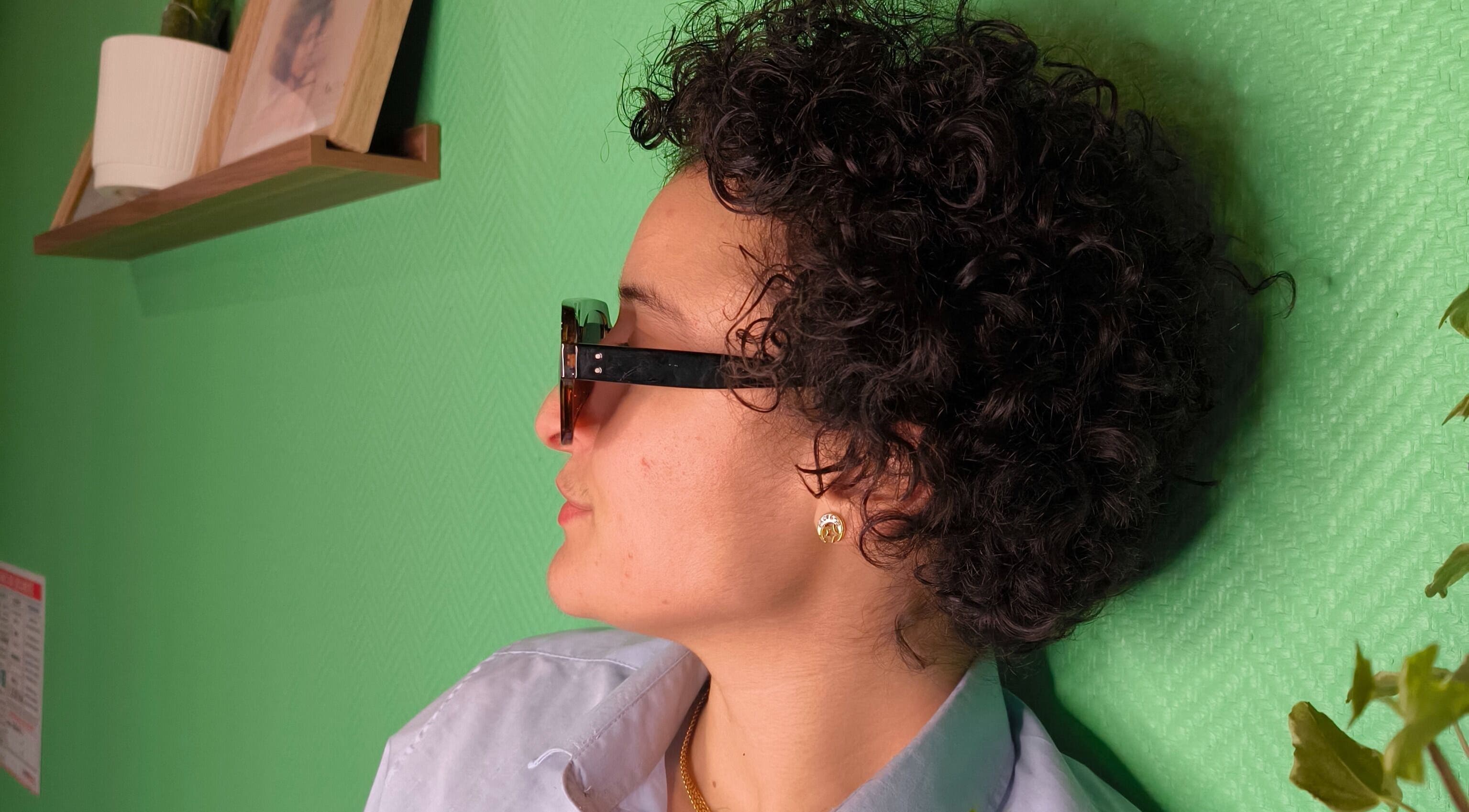 Client avec cheveux bouclés à Locksandcurlsstudio, Orléans, Centre-val De Loire, FR. Style moderne sur fond vert.