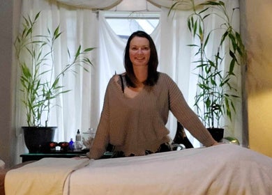 Massage therapist at Massage with Liz, LLC in Springfield, Oregon, US, stands beside a massage table.