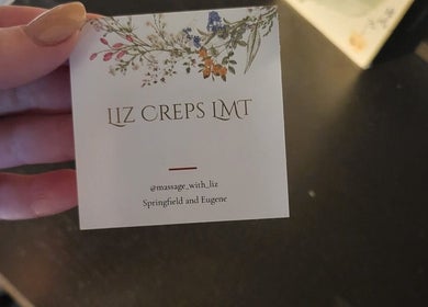 Close-up of a business card for Massage with Liz, LLC, Springfield, Oregon, US, showing floral accents.