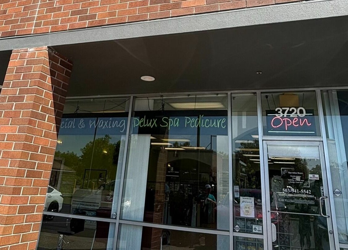 Entrance of Great Professional TA Nails spa in Beaverton, Oregon, US, showcasing glass doors and brick facade.