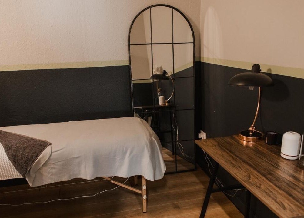 Cozy treatment room at Vs Skin, Glasgow, Scotland, GB. Features a massage table, elegant mirror, and modern decor.