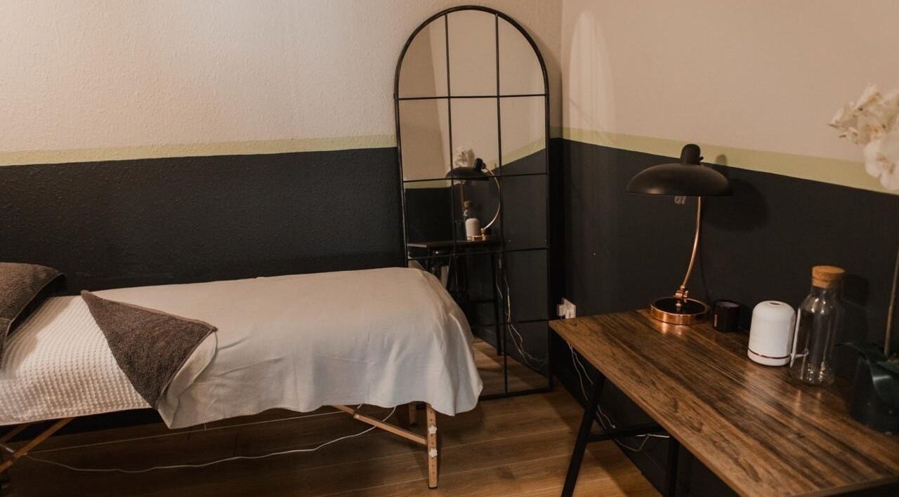Cozy treatment room at Vs Skin, Glasgow, Scotland, GB. Features a massage table, elegant mirror, and modern decor.