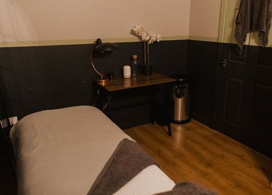 Cozy treatment room at Vs Skin, Glasgow, Scotland, GB, featuring a bed, table, and ambient lighting.