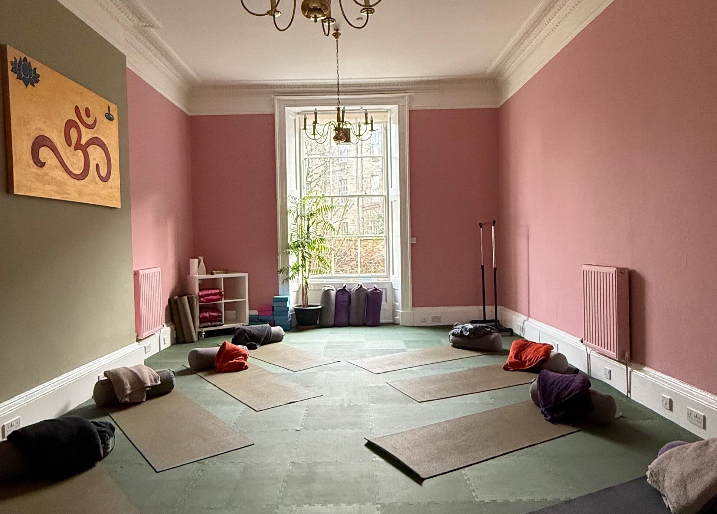 OMH Wellness Studio yoga space with mats and cushions, Edinburgh, Scotland, GB, pink walls and window view.
