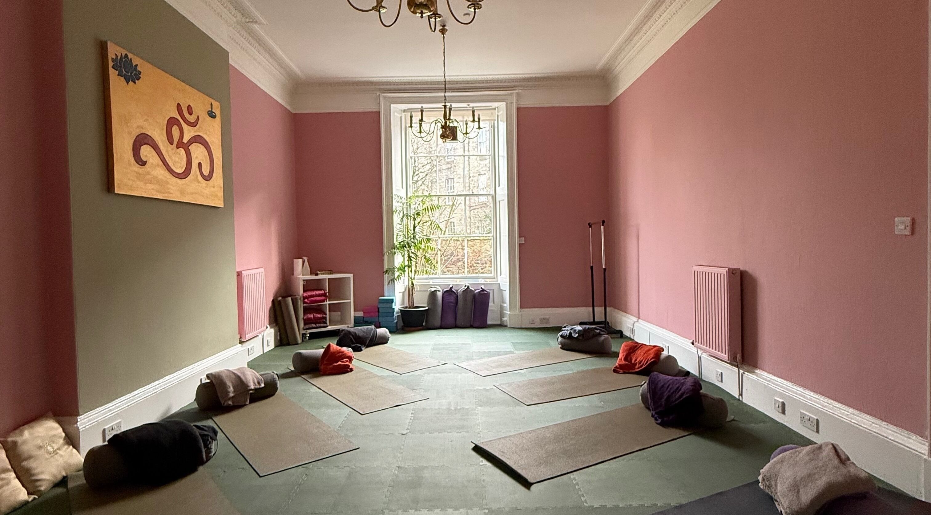 OMH Wellness Studio yoga space with mats and cushions, Edinburgh, Scotland, GB, pink walls and window view.