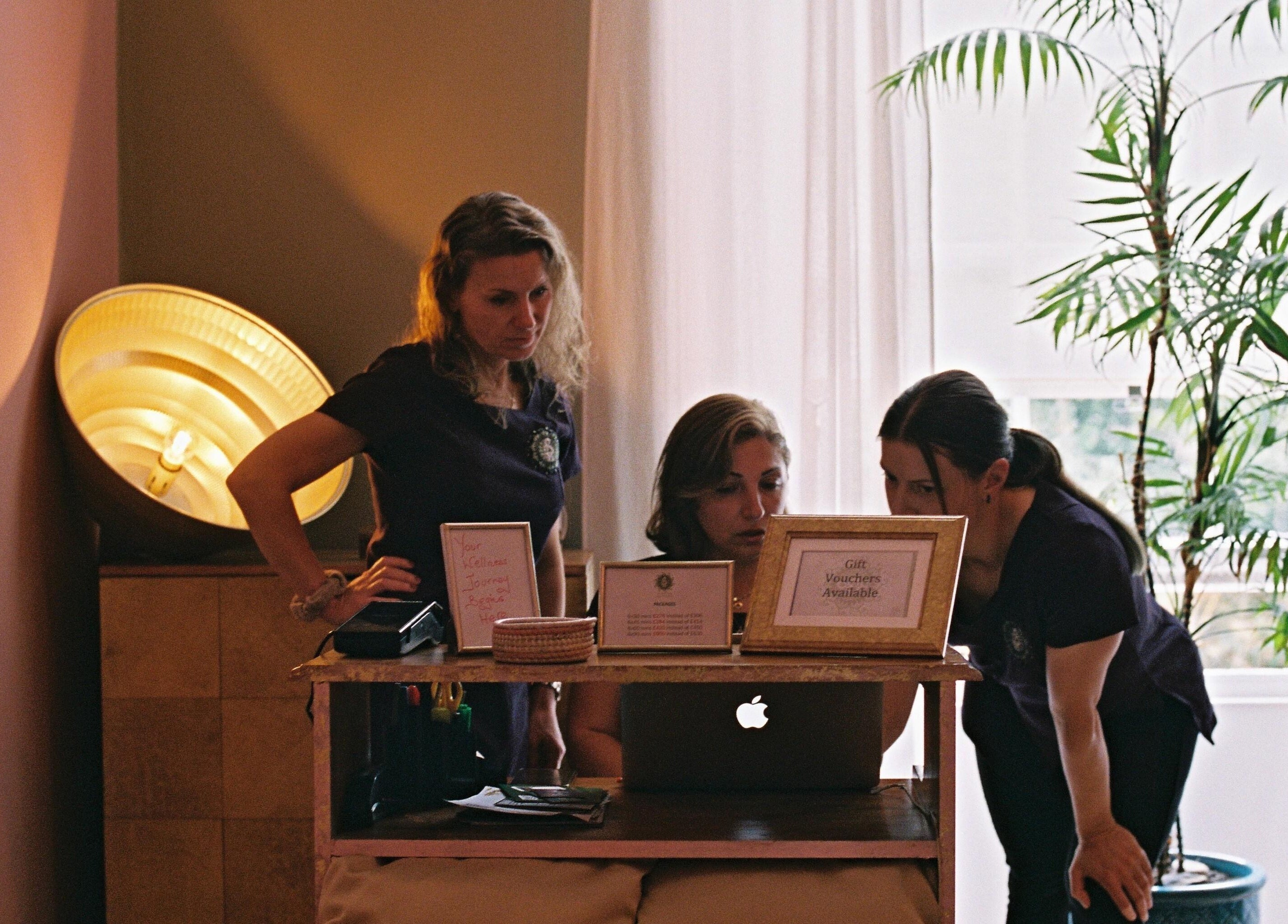 Staff at OMH Wellness Studio in Edinburgh, Scotland reviewing information at a warmly lit reception desk.
