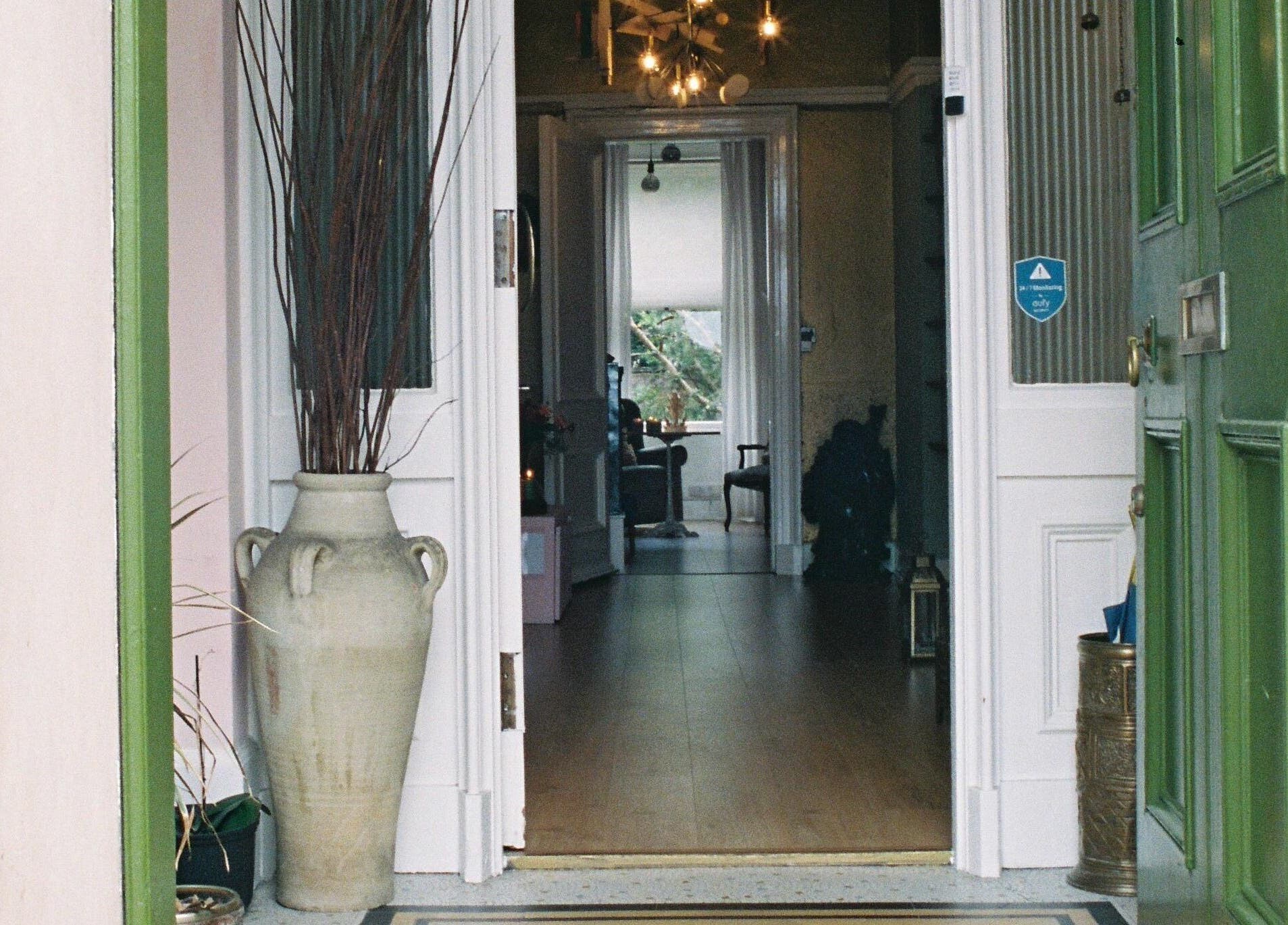 Inviting entrance of OMH Wellness Studio, Edinburgh, Scotland, GB with a green door and decorative vase.