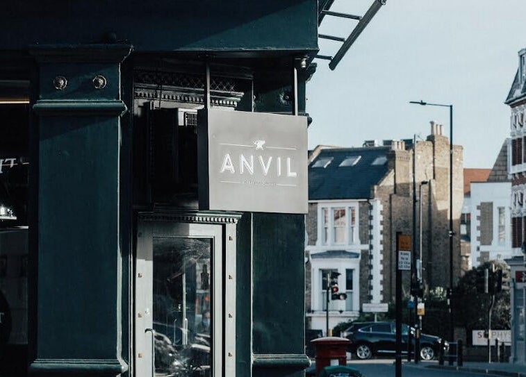 Exterior of Anvil Barbers located on a bustling street in London, England, GB with charming shopfront.