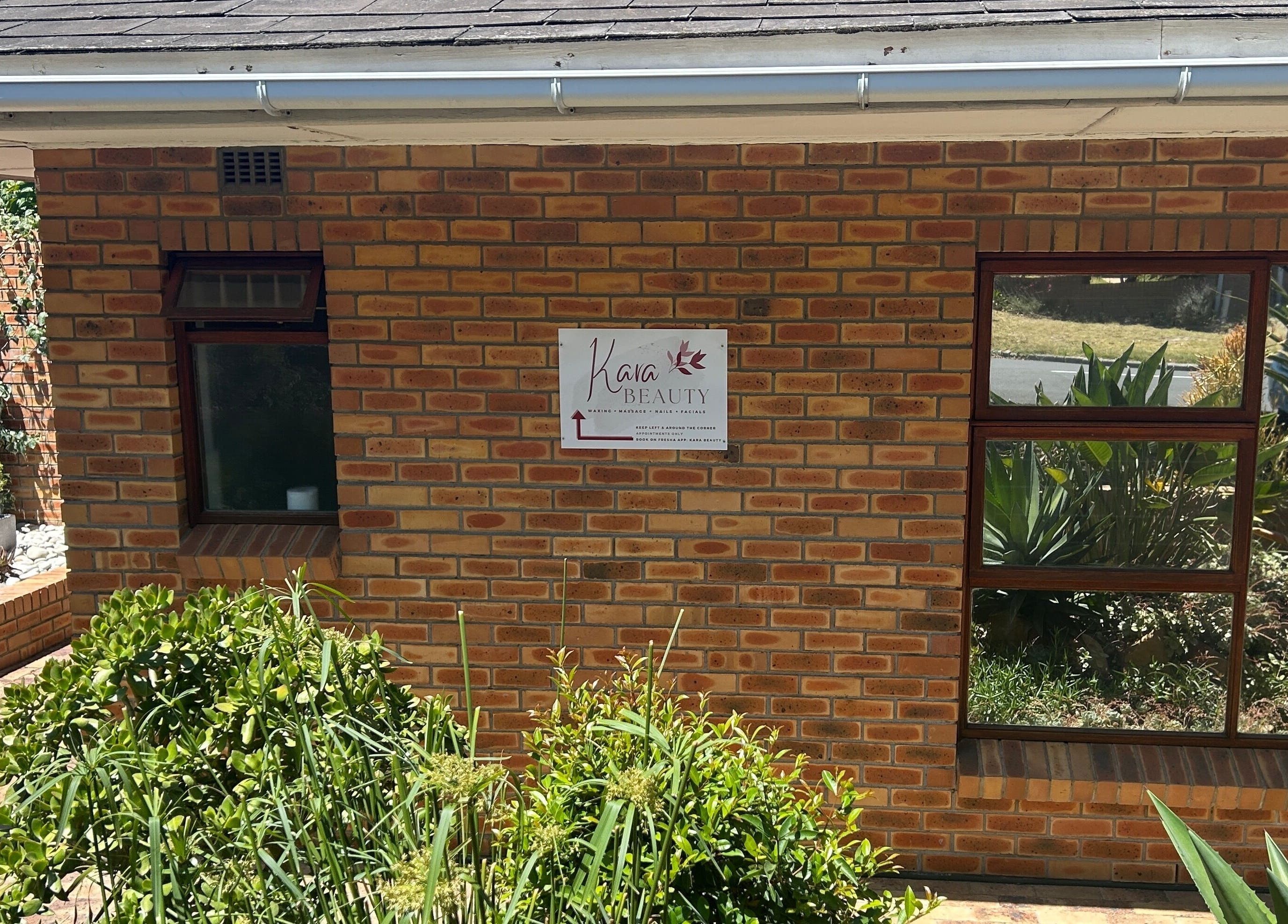 Front view of Kara Beauty in Cape Town, Western Cape, ZA, showcasing brick exterior and lush plants.