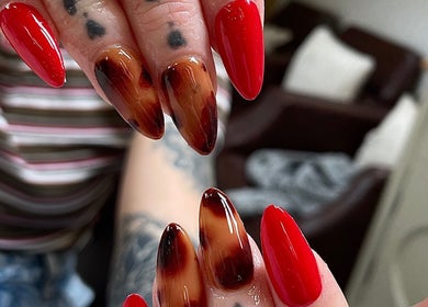 Vibrant red and brown nail art showcased at Evergreen Beauty, Desborough, England, GB.