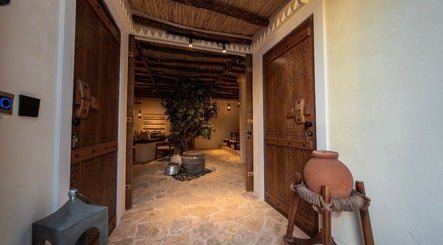 Entrance to Hisma Spa in Riyadh, showcasing a warm, rustic design with wooden doors and stone flooring.