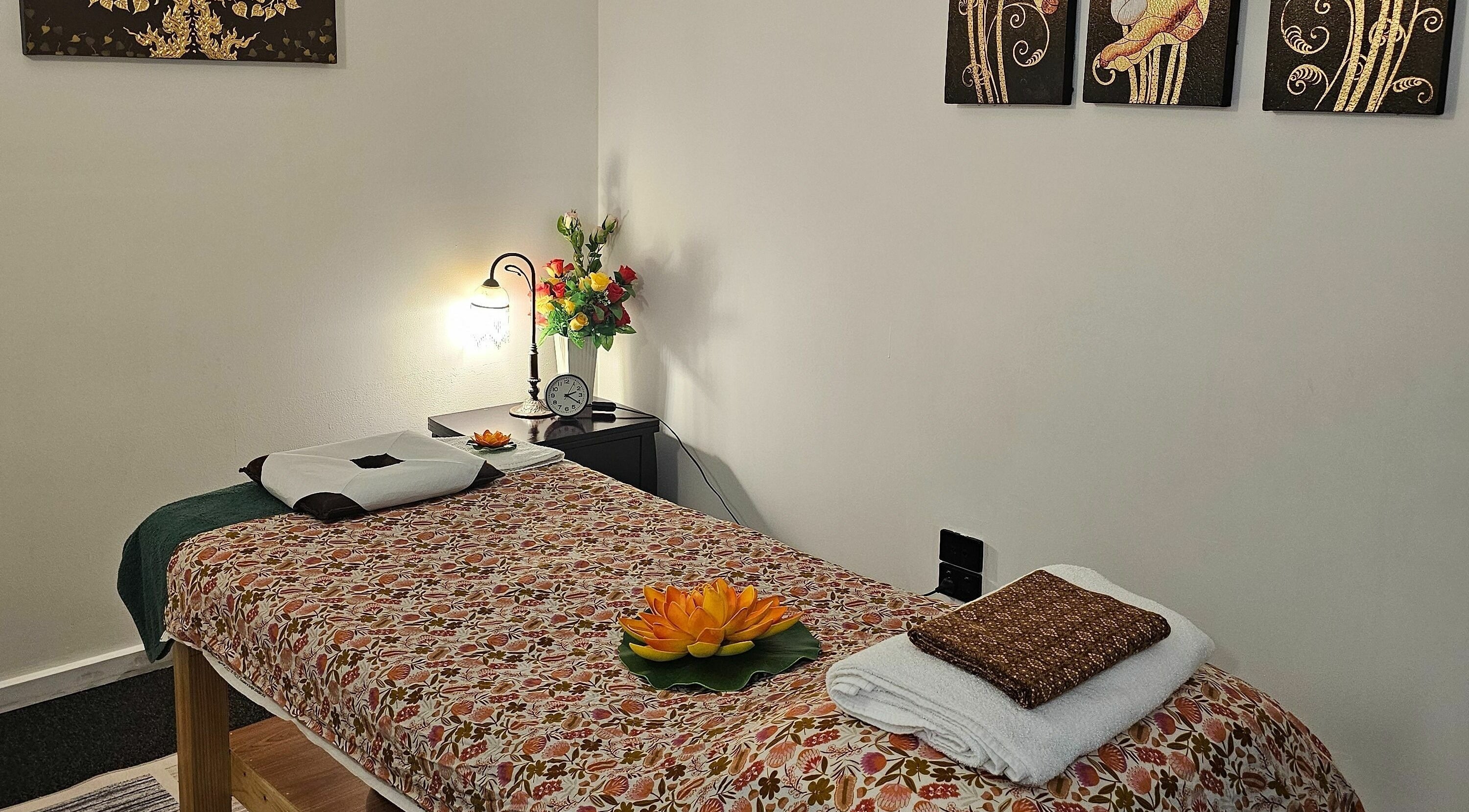 Calm massage room at Gold Leaf Thai Massage, West Melbourne, Victoria, AU with a floral bedspread and soft lighting.