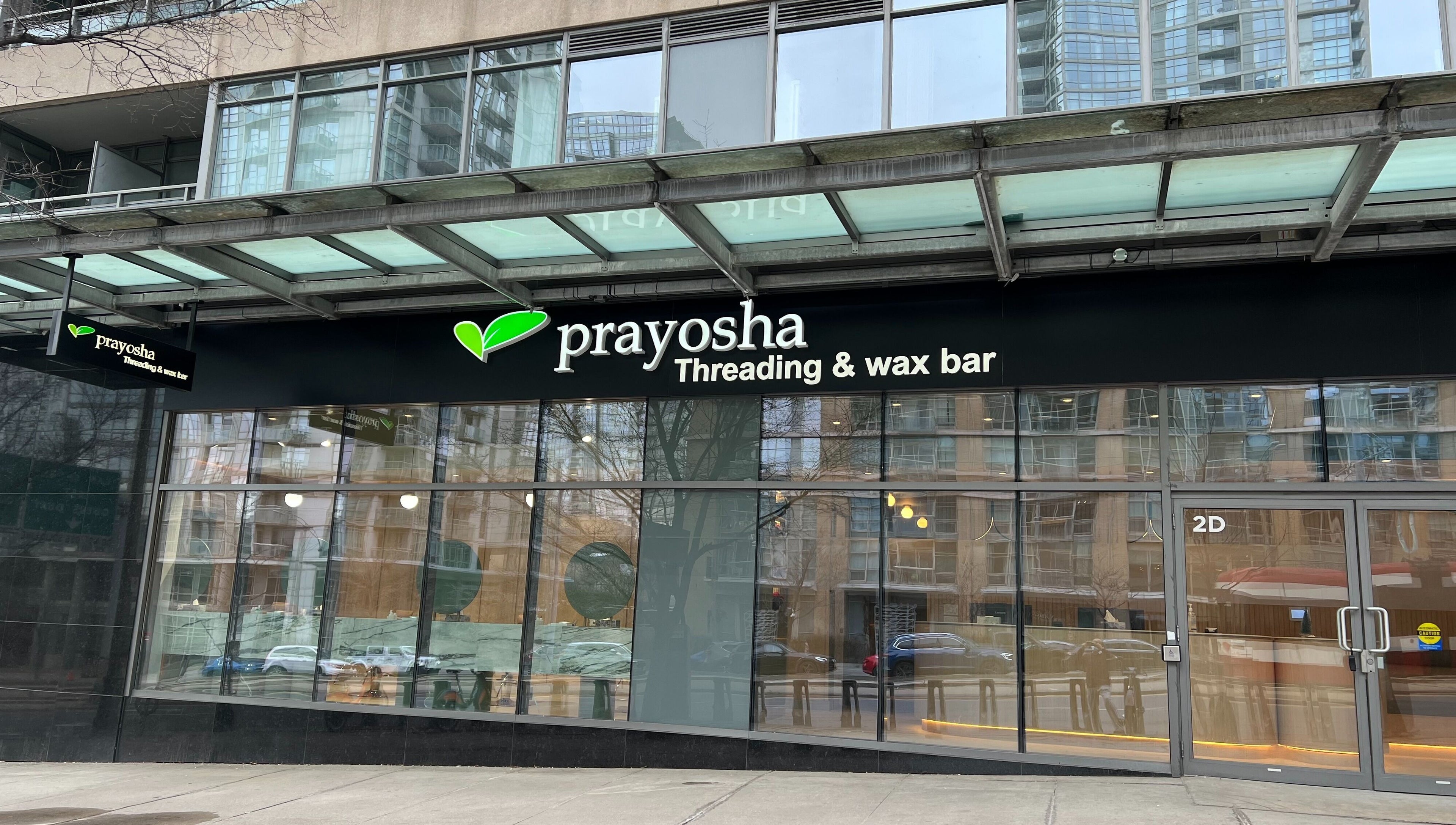 Exterior of Prayosha Threading & Wax Bar @ Spadina in Toronto, Ontario, CA with modern glass facade.