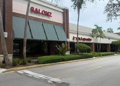 Fachada de Lismynails Salon & Spa en Plantation, Florida, US rodeada de palmeras y arbustos.