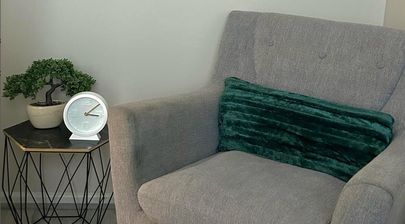 Elegant gray chair with green cushion beside a plant at Lash Lunar, Cape Town, Western Cape, ZA.