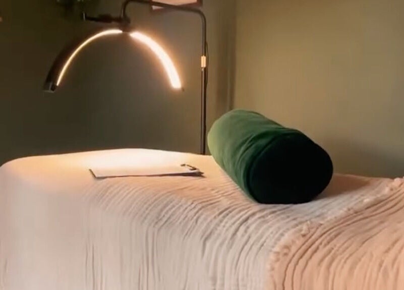 Cozy spa bed at Om Holistic - The Studio, Leeds, England, GB with soft lighting and plush green bolster.