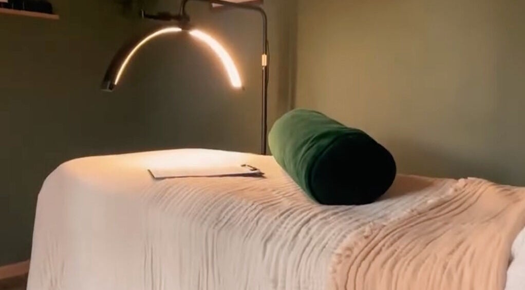 Cozy spa bed at Om Holistic - The Studio, Leeds, England, GB with soft lighting and plush green bolster.