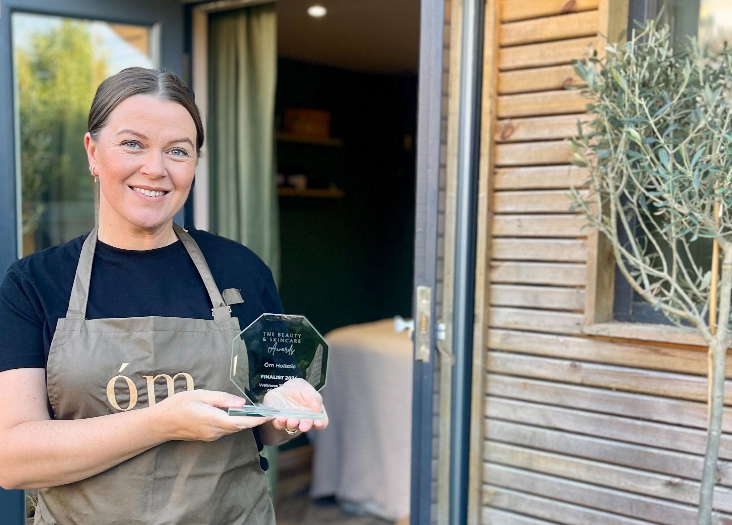 Om Holistic - The Studio, Leeds, England, GB: Person proudly holding a beauty award in front of stylish venue.