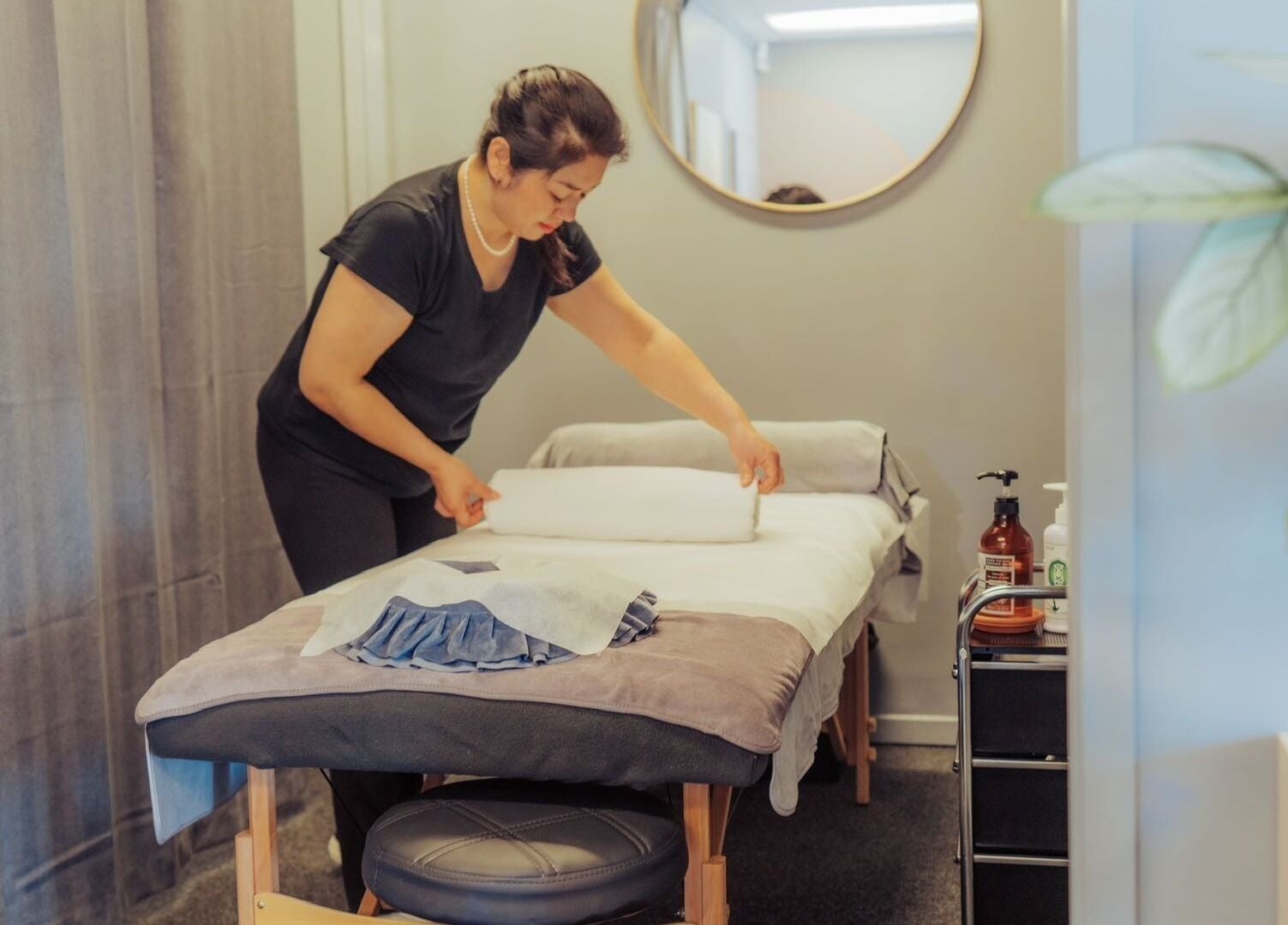 Staff preparing massage bed at JM's Massage, Auckland, NZ, showcasing serene and welcoming ambiance.
