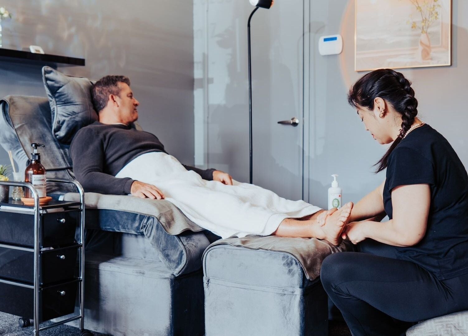 Foot massage at JM's Massage, Auckland, Auckland, NZ. Client relaxes on plush chair.