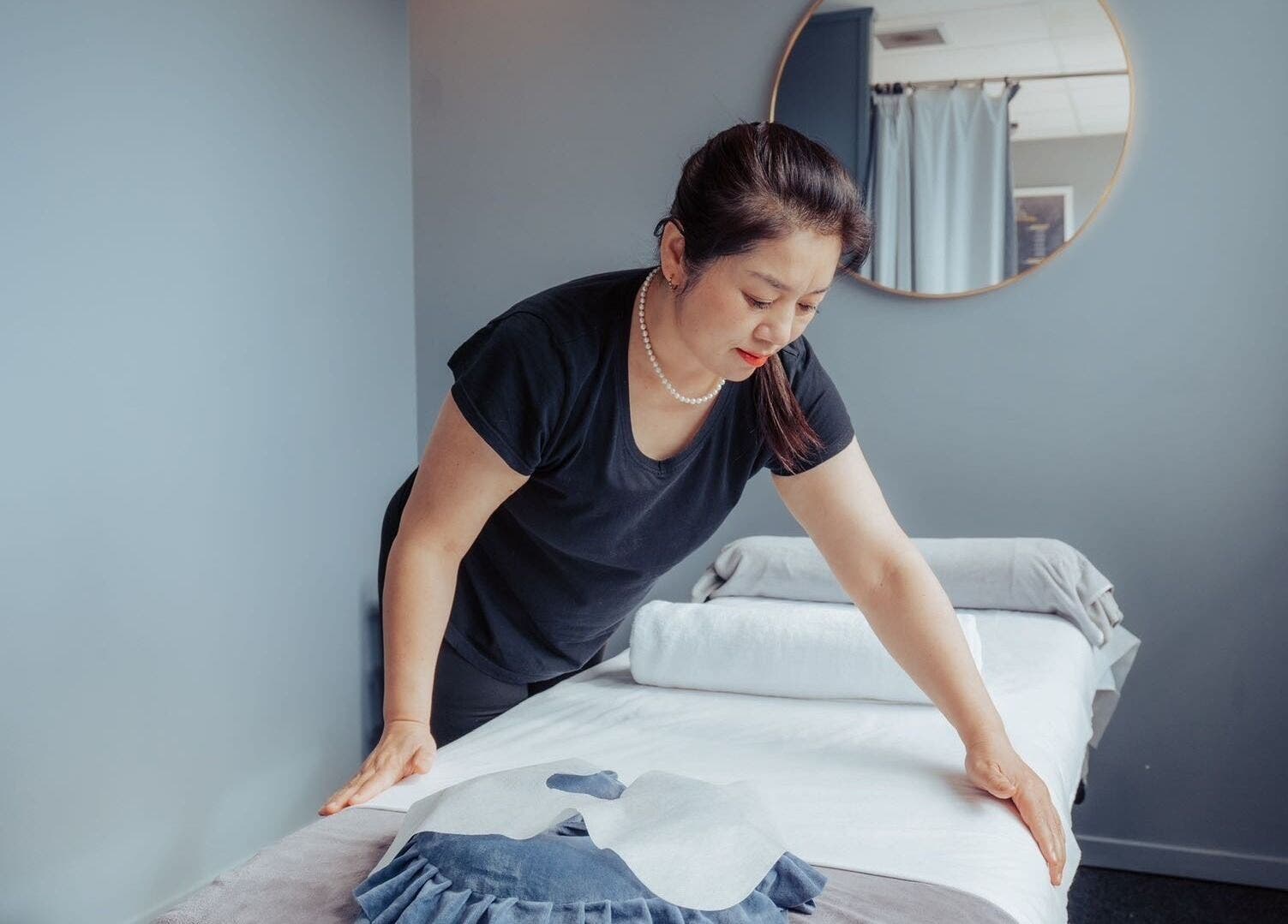 Staff preparing massage table at JM's Massage, Auckland, Auckland, NZ, ensuring a relaxing experience.