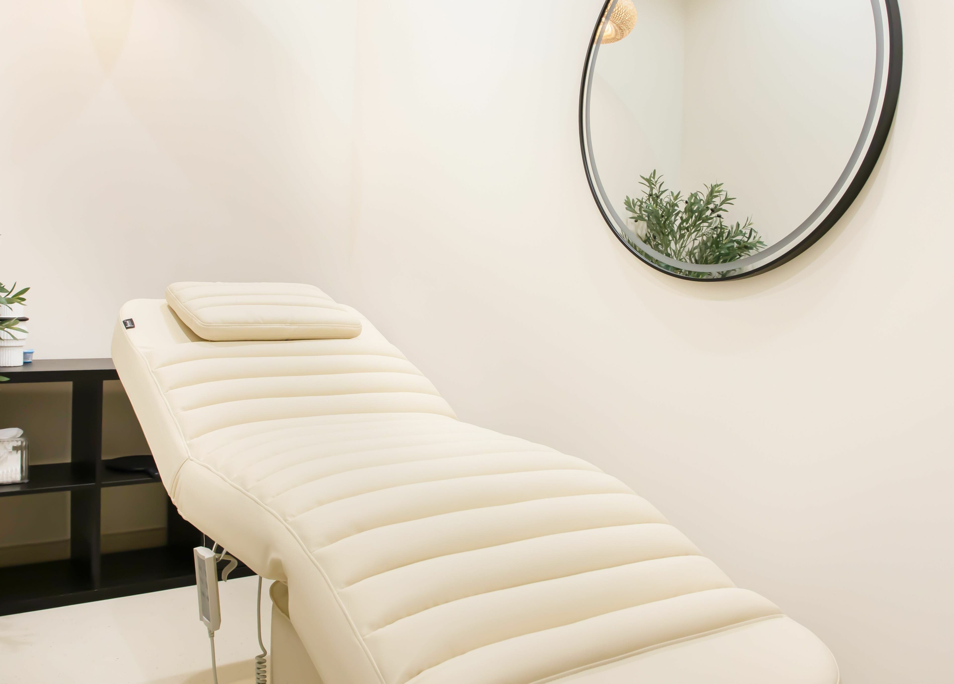 Relaxing treatment room at AND14 with a plush massage bed, mirror, and greenery in دبي, دبي, AE.