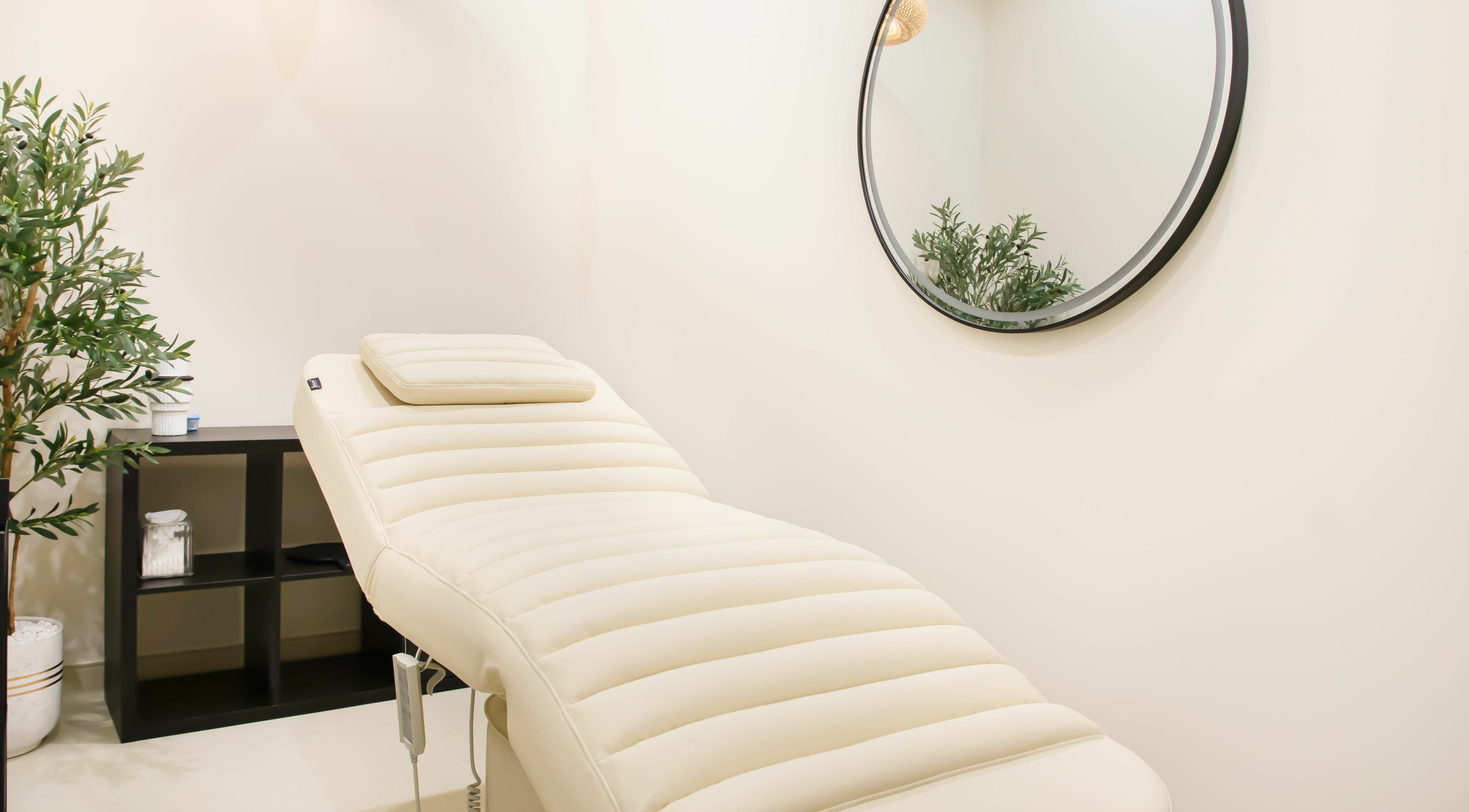 Relaxing treatment room at AND14 with a plush massage bed, mirror, and greenery in دبي, دبي, AE.