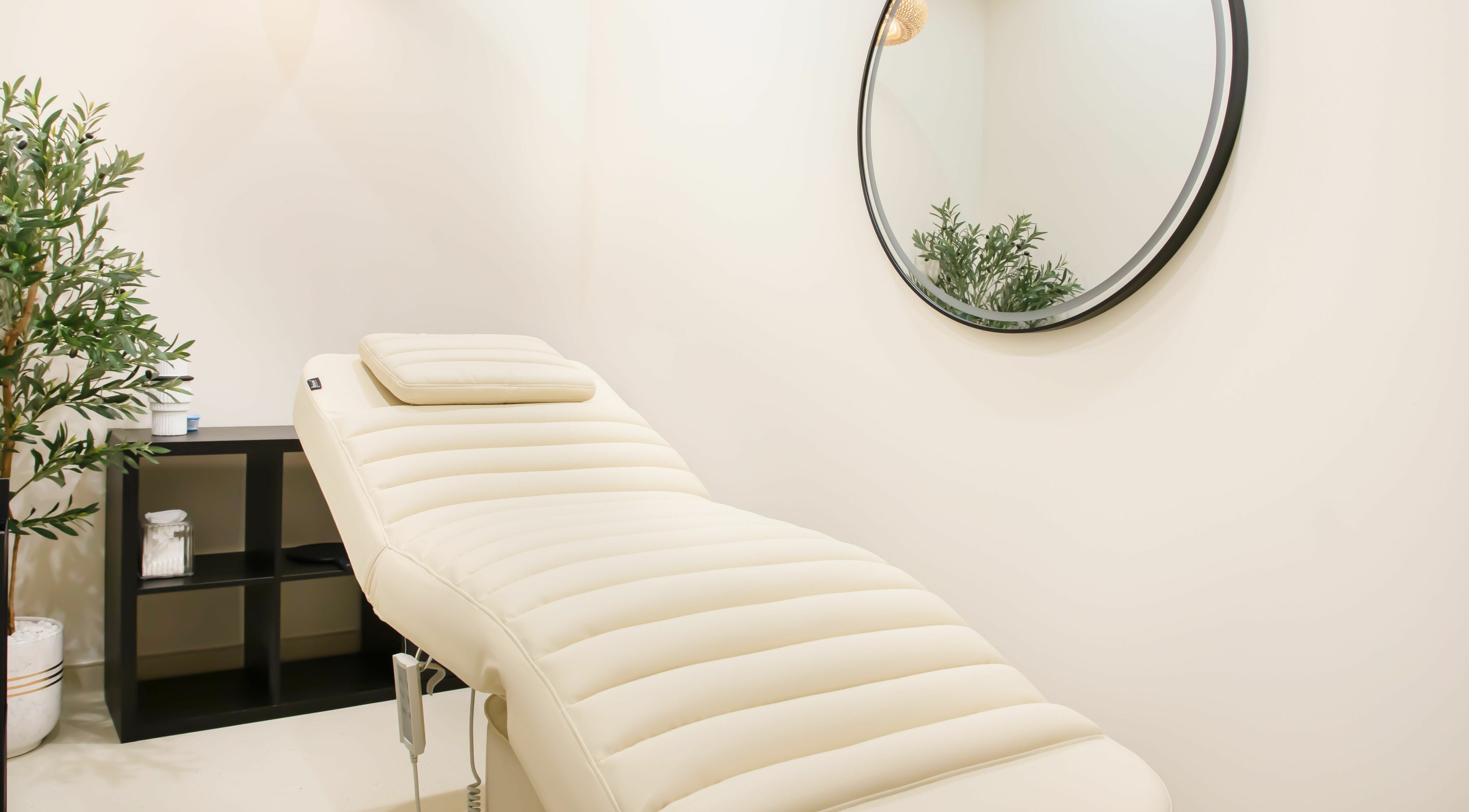 Relaxing treatment room at AND14 with a plush massage bed, mirror, and greenery in دبي, دبي, AE.