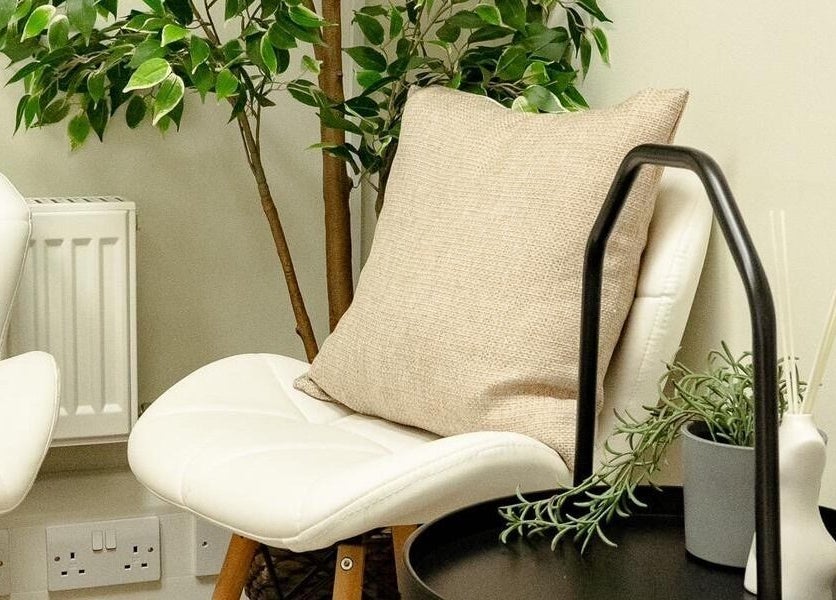 Relaxing seating area at Natalie Aesthetics, Great Shelford, England, GB, featuring white chairs and greenery.