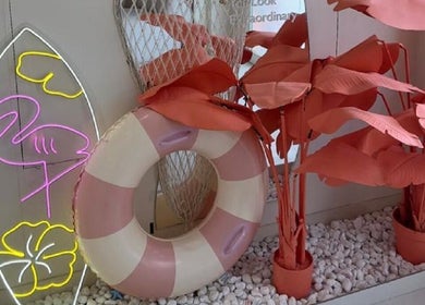 Unique tropical decor at Rare Beauty Saloon, Ajman, AE, featuring neon flamingo lights and vibrant foliage.