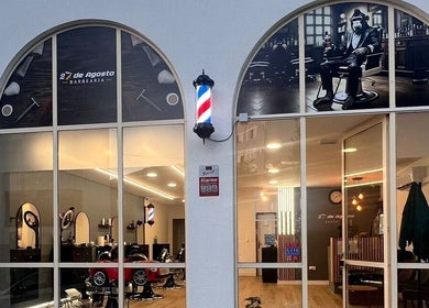 Entrada iluminada da Barbearia 27 De Agosto em Braga, Braga, PT, destacando o interior moderno e acolhedor.