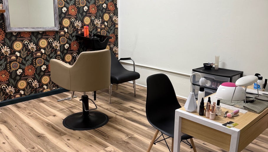 Cozy salon interior at Wild Roots Studio, Easley, South Carolina, US with floral wallpaper and styling stations.