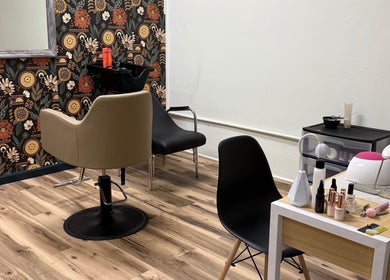 Cozy salon interior at Wild Roots Studio, Easley, South Carolina, US with floral wallpaper and styling stations.