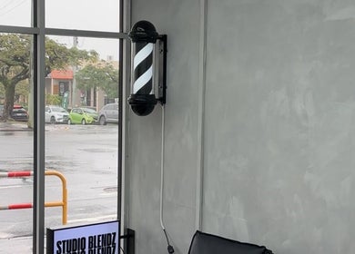 Interior window view at Studio Blendz, showcasing a stylish barber pole in Southport, Queensland, AU.