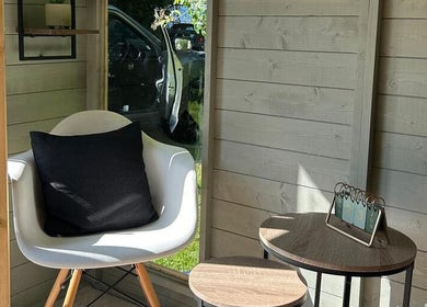 Chic seating area at Izzy’s Beauty Room in Gloucester, England, GB, featuring a modern chair and side tables.