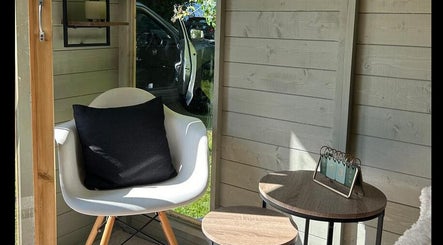 Chic seating area at Izzy’s Beauty Room in Gloucester, England, GB, featuring a modern chair and side tables.